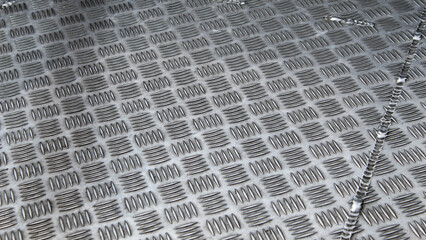 Obraz premium A close-up shot of a textured silver aluminum checker plate with a raised bar pattern and a metallic weld seam. industrial background.