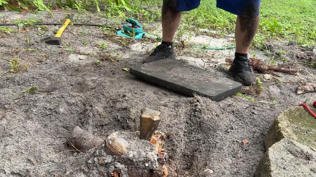 Homeowner Using Sledgehammer to Break Apart Tree Stump in Backyard