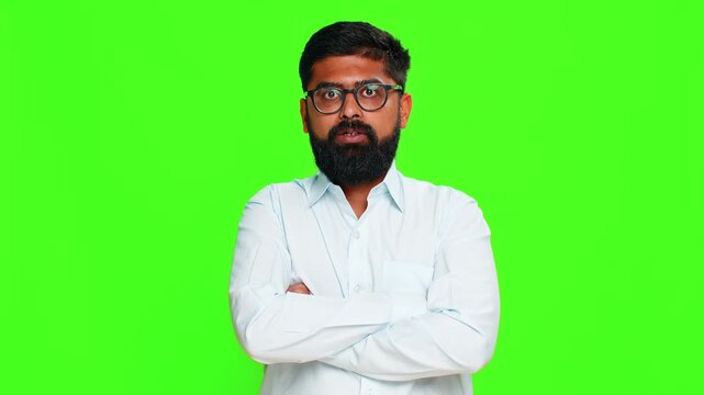Indian man crosses arms looks strictly with serious face, showing authority confident attitude in dominant posture. Arabian guy isolated on green chroma key background expressing firmness and control