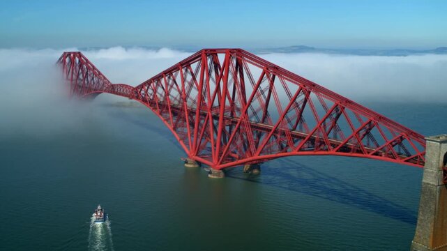 Beautiful aerial view of the historic Forth Bridge emerging from the fog on a sunny day