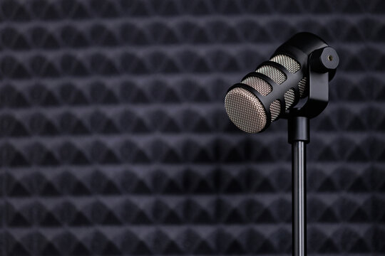 Professional studio microphone on a stand in a soundproof room with copy space.