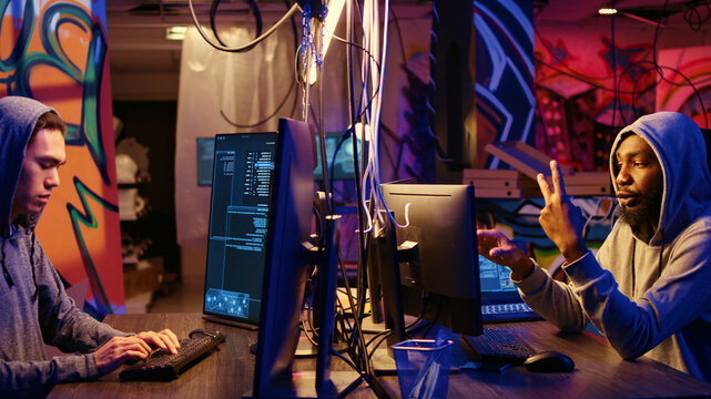 Experienced hackers writing lines of code in computers from their underground bunker, discussing ways of getting past security systems, rogue programmers building scripts that can hack devices.