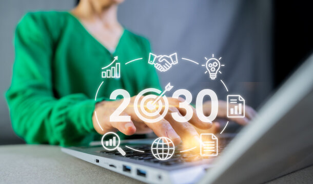 Businesswoman typing on laptop with year 2030 target goal and business strategy plan concept.