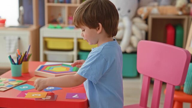 Boy placing number cards and wooden puzzle pieces with his hands on a red table in building; concentration learning.