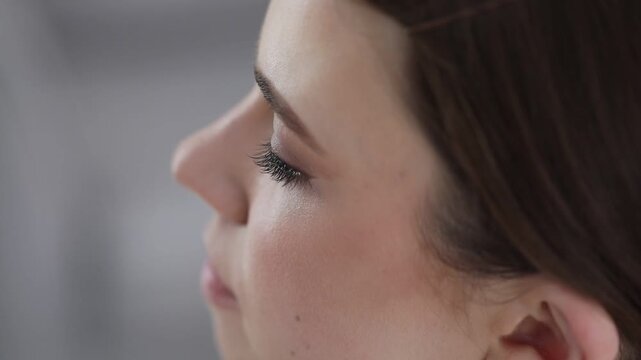 Makeup artist applying false eyelashes on woman's face indoors, closeup