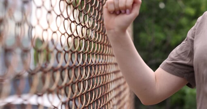 Human trafficking. Woman trying to escape captivity near fence outdoors, closeup