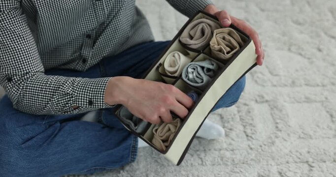 Man putting socks into organizer on floor at home, closeup
