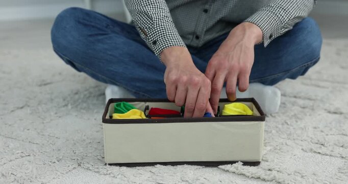 Man putting socks into organizer on floor at home, closeup