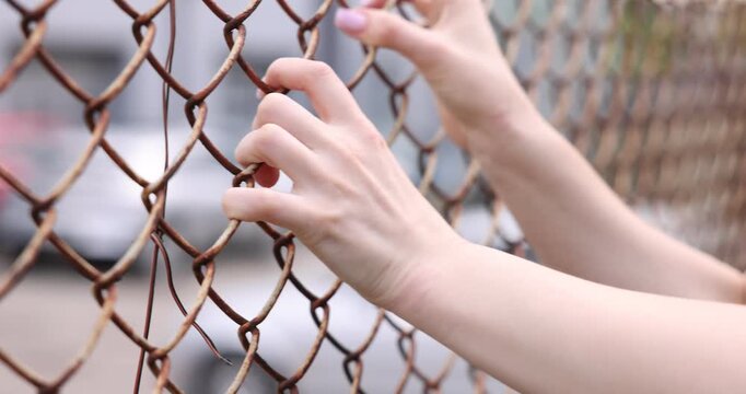 Human trafficking. Woman trying to escape captivity near fence outdoors, closeup