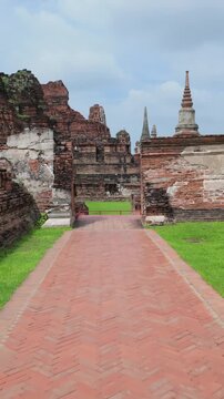 The ancient ruins of Wat Mahathat in Ayutthaya, Thailand, showcase weathered brick structures and stupas under a cloudy sky, offering a glimpse into historical grandeur.