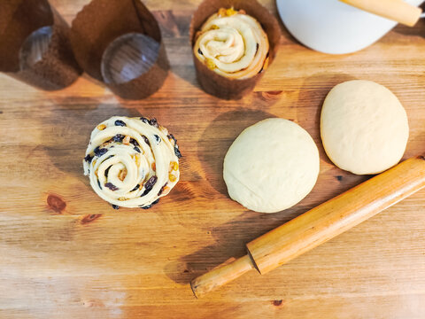Homemade Cruffins. Unbaked Shaped Cruffin in Paper Baking Cup with Dough Balls and Wooden Rolling Pin on a Wooden Table