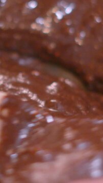 Vertical Video Stirring Homemade Chocolate Brownie Mix in Glass Bowl with Wooden Spoon in Slow Motion &ndash; Close Up. Glossy fudge batter, perfect for cooking tutorials and recipe video concepts. 4K.
