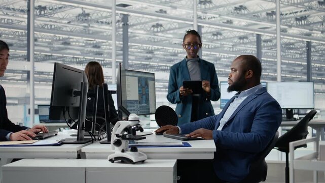 Man and woman modeling integrated circuit systems with PC software in R&D office, African American coworkers use computer to optimize microchip hardware manufacturing in tech laboratory.