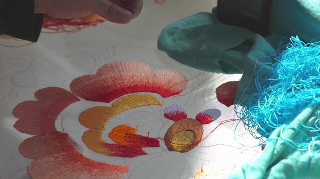 Close-up of Qiang ethnic woman's hands embroidering traditional floral pattern in Beichuan, Sichuan, China