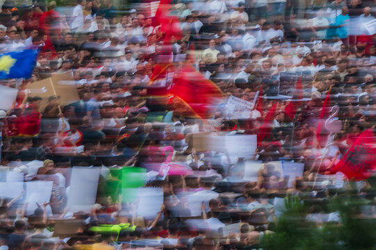 Tirana, Albania - 03 June 2026: View of a protest with a large crowd of people holding Albanian flags and placards with motion blur effect.