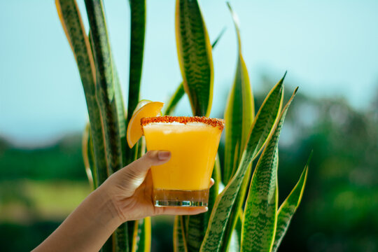 Vaso de jugo de naranja sostenido por una mano