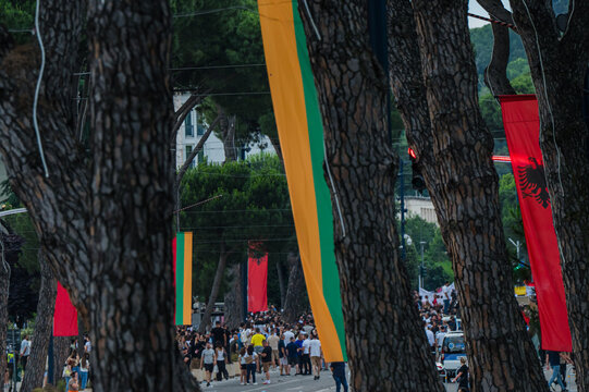 Tirana, Albania - 03 June 2026: View of a large crowd of people gathered for a protest on a city street lined with trees and Albanian national flags.