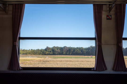 View from inside a vintage Japanese local train with pink curtains
