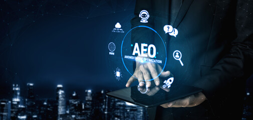 Obraz premium Hands of a business professional interacting with AEO concept on a digital tablet against a futuristic city skyline background at night Fluxor.