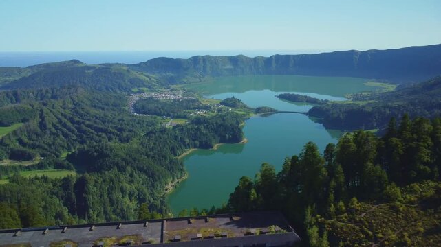 Aerial drone reveal of volcanic caldera lake across green crater rim