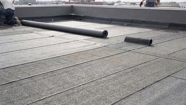 Medium shot of twoply modified bitumen roofing installation on flat commercial roof showcasing layered membrane rolls and precise seam alignment.