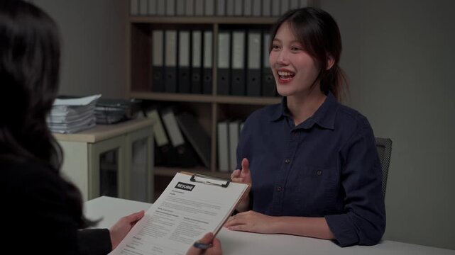 Young asian job applicant presenting her resume to a recruiter