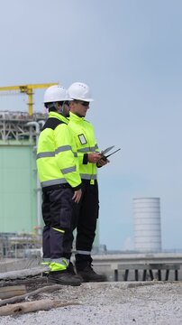 Engineer inspection industrial safety hardhat high visibility clipboard, construction team review checklist and tablet, refinery power plant worksite maintenance planning, compliance audit