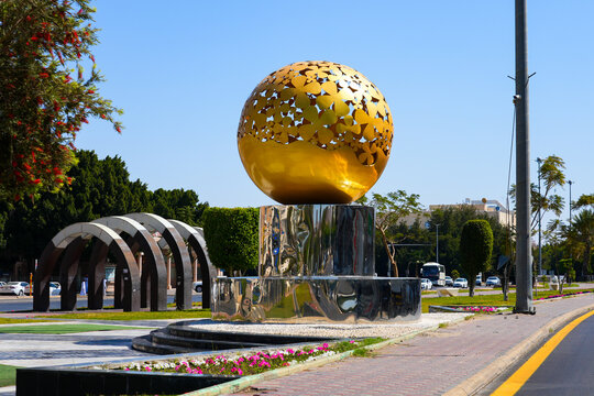 Modern public monument with golden flower patterned sphere and mirror base in Taif, Saudi Arabia