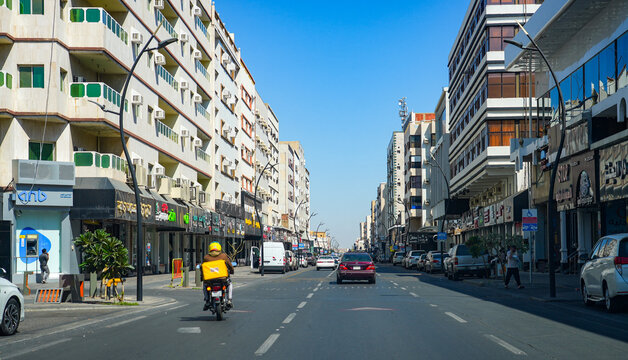 Street view with car traffic, delivery motorcycle and modern buildings in Taif city, Saudi Arabia