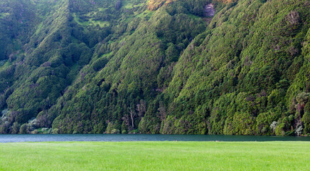 Naklejka premium Sete Cidades volcanic crater lakes. Lush green hills surround twin lagoons. Dense forest covers steep caldera walls. Scenic Azores landscape in Portugal's San Miguel Island.