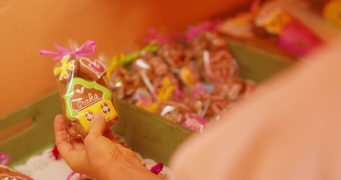 Hand choosing a small packaged gingerbread house cookie with text Praha at a souvenir shop store in Prague Czech Republic