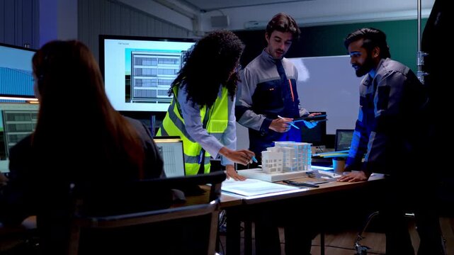Engineering professionals reviewing architectural plans and digital project documents during collaborative technology development meeting in modern office