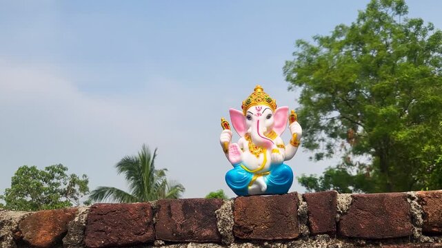 Beautiful ganesha idol placed on brick wall against clear blue sky outdoor footage.