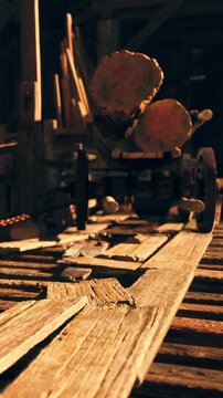 Workers are active in a wooden workshop. Tools are scattered on the floor. Logs are stacked in the background. Evening light filters through the space, casting shadows.