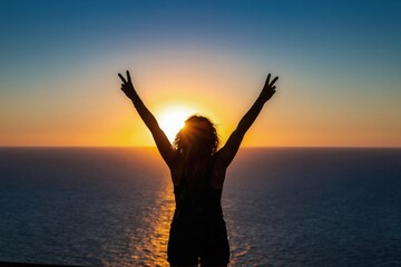 Fototapeta premium Woman silhouette with arms raised in victory gesture on sea horizon at golden sunset. Person enjoys ocean view with bright sun. Freedom hope and vacation mood.