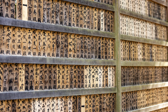 View of numerous traditional wooden plaques with Japanese calligraphy arranged in rows at a historic temple site in Nara, Nara, Japan.