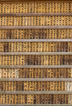 View of traditional wooden plaques with Japanese calligraphy arranged in rows at a Shinto shrine in Nara, Nara, Japan.