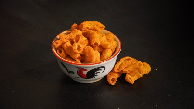 Bowl of Crunchy Corn Puff Snacks on Dark Background