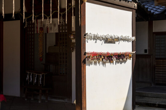 View of traditional wooden prayer plaques and tied paper fortunes on a white wall at a Japanese shrine in Nara, Nara, Japan.