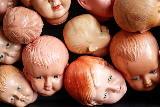 Collection of vintage doll heads scattered against a dark background