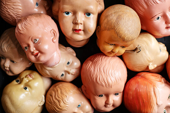Collection of vintage doll heads scattered against a dark background
