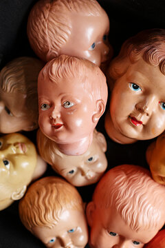 Collection of vintage doll heads scattered against a dark background