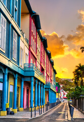 Naklejka premium Vibrant row of multi-colored buildings and traditional shutters at sunset along a street in Fort-de-France, Martinique, Caribbean France
