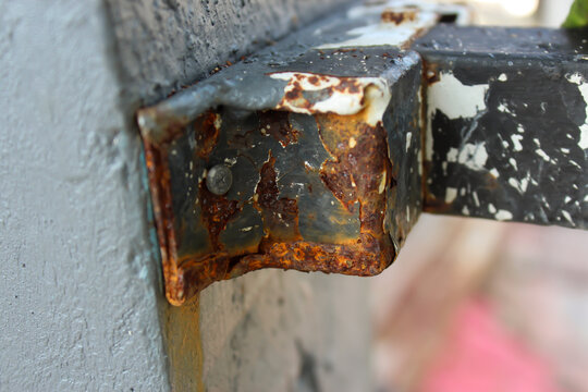 Close Up of Rusted Metal Bracket Attached to Concrete Wall Showing Corrosion and Weather Damage