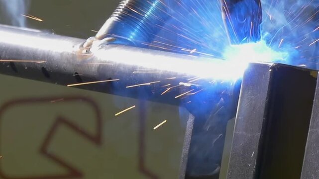 Witness the artistry of an industrial argon welding robot in action. The close-up captures the bright blue arc and sparks, creating a mesmerizing display of skill and technology over metal seams.
