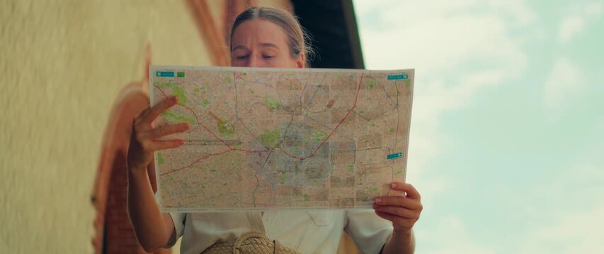 Tourist reading a city map outdoors in Milan city under a bright blue sky
