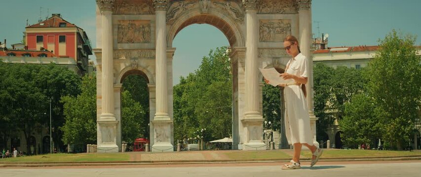 Tourist walking in front of Arco della Pace with city map in summer Milan Italy
