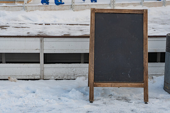 A blackboard standing on a wooden frame, potentially outdoors amidst snowy surroundings The board is clean and uncluttered with no visible texts or objects