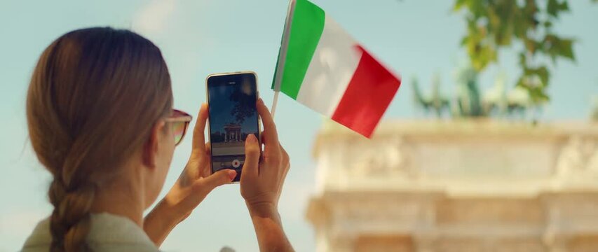 Tourist photographing the Arco della Pace in Milan with an Italian flag and copy space background
