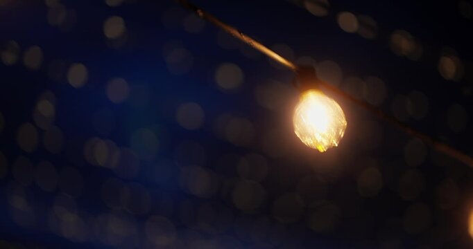 Warm glowing string lights hanging over a dark outdoor scene